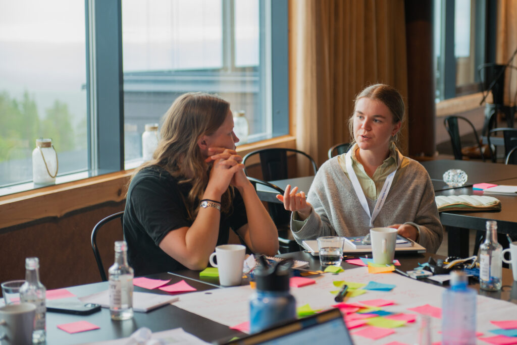 Two Arctic Youth Dialogue participants sitting at a table with post-it notes, talking